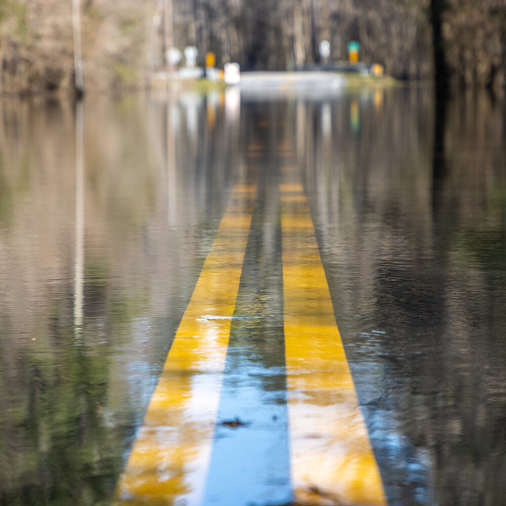 Camino inundado bajo el agua después de fuertes lluvias A road is unpassable to cars after a nearby river overtopped its banks after days of rain, flooding it. South Carolina.