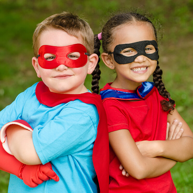 Pretty mixed race girl and Caucasian boy pretending to be superheroes